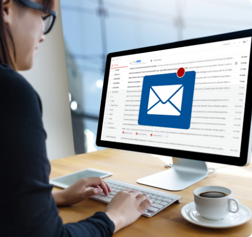 Imagen de una mujer sentada frente a una computadora recibiendo un correo electrónico nuevo